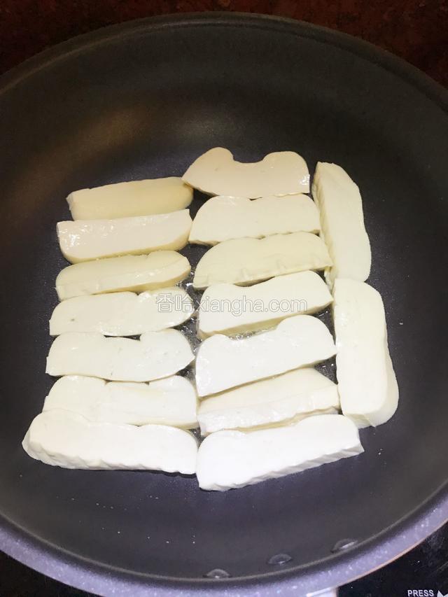 切好的豆干摆放整齐在煎锅中，全程小火慢煎。