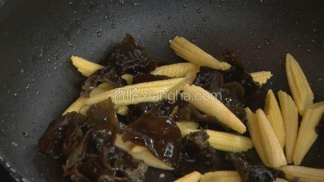 在锅里加入一点底油，倒入木耳，玉米笋进行翻炒
