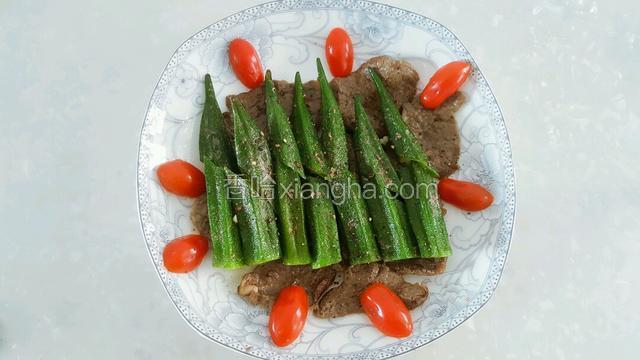 将秋葵摆到牛肉上，再撒上黑胡椒，盘边摆上小番茄点缀。