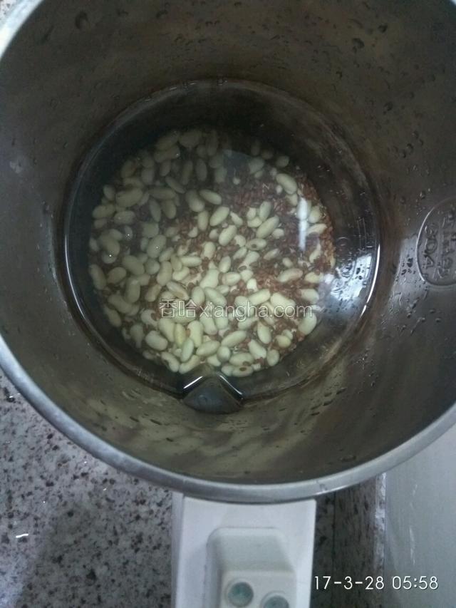 把泡黄豆洗干净，和泡过的亚麻籽一起放豆浆机中，加入适量的水。