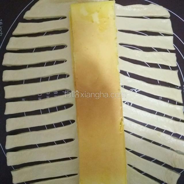 取一个面团擀成长方形，跟蛋糕一样的长度，把蛋糕放中间，用切面刀从两边切出一样的十条长度