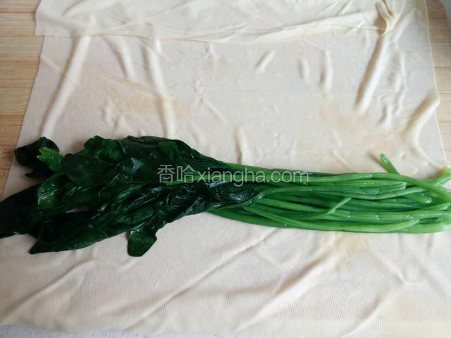 干豆腐平铺在菜板上，上面放菠菜码好。