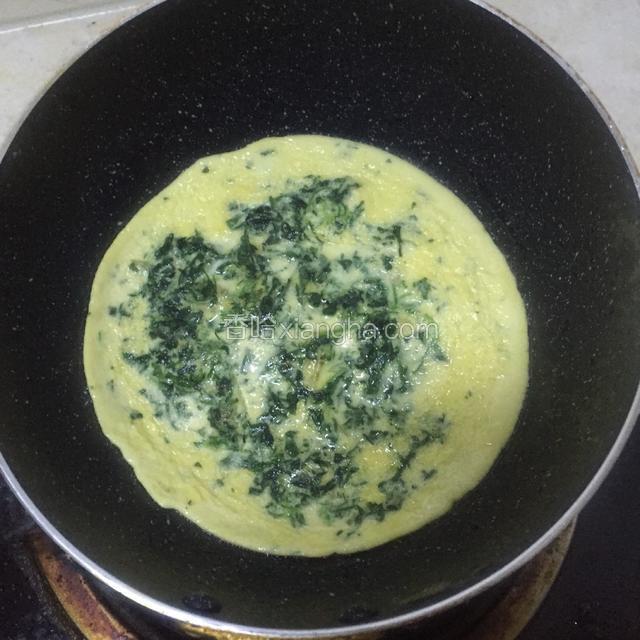 将混合好的菜蛋液缓缓倒入炒锅，铺满一层底即可，无须太厚，摇晃均匀，小火慢慢煎。