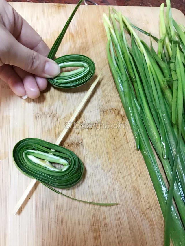 取适量韭菜如图，从根部开始卷起，卷好后用竹签串起来。