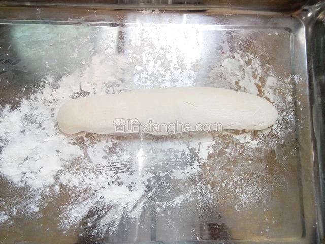 在板上撒点面粉可以防止面团沾，把醒发好的面团揉成长条状。