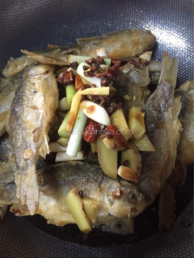 将煎好的小鱼放入锅中撒入准备好的调料