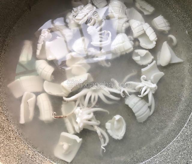 锅里水烧开，放入料酒，倒入鱿鱼，看到鱿鱼卷起来了迅速捞起备用