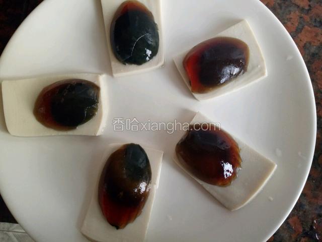 皮蛋剥好在开水里焯一下去除脏气，把皮蛋竖着对半切开做金鱼的中间身体，如果盘子小，皮蛋要竖着从三分之一处切，这样可以让皮蛋小一些，把切好的皮蛋依次摆在豆腐上