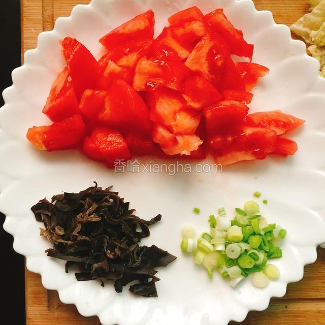 将去皮的西红柿切成小块、木耳切丝、葱切花放在盘中备用