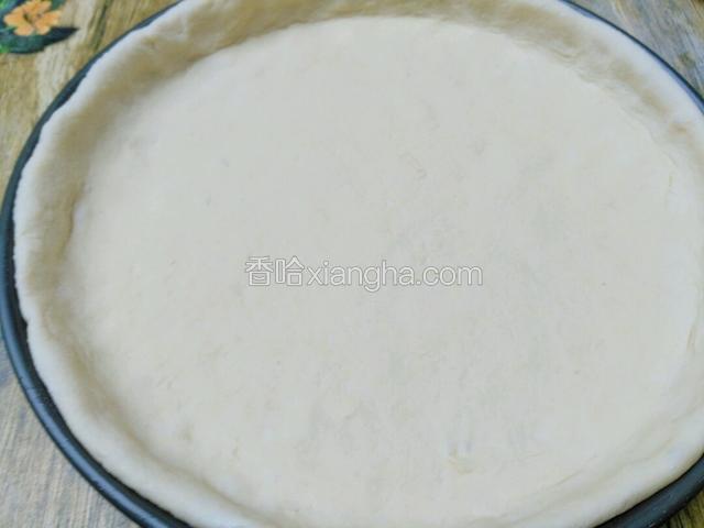 醒好面团，擀成圆饼放披萨盘子里，面饼最好比披萨盘高出一两分，再按回周边面饼跟盘子一样高度，这样做的目的是饼边边比较厚厚的好看。之后再二次醒发一会，