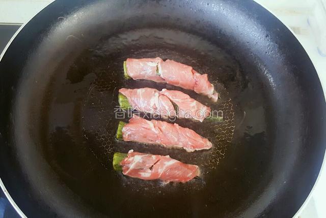 把牛肉秋葵卷依次放入平底锅内，改用中小火煎制。