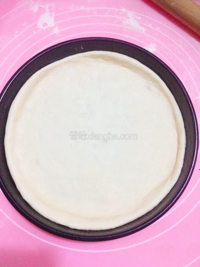 把饼皮放进披萨盘里，用手整成中间薄边上厚的样子。