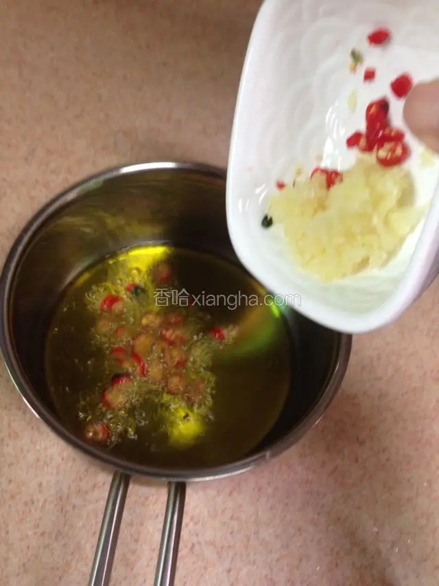 油温滚热后关火离灶放入小米辣和蒜末，利用余热爆香。