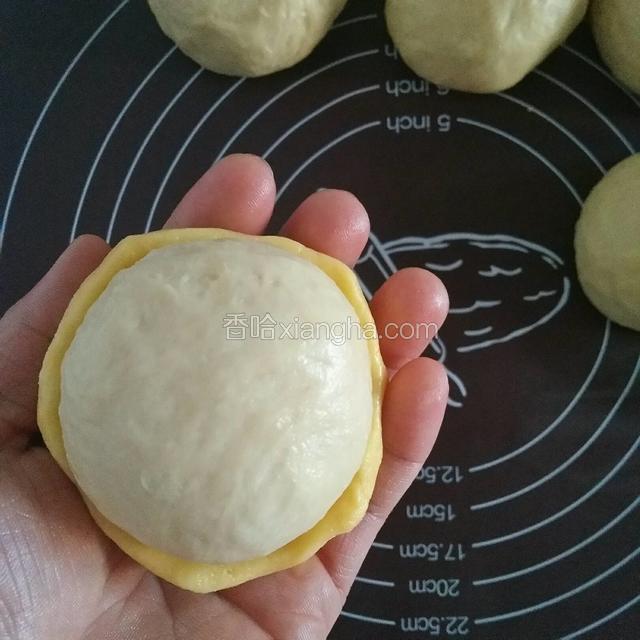 醒发好的面包胚分成九等份，取一份酥皮和面团放一起，将面团轻轻的往酥皮里压，边压边收拢面团，至酥皮包住面团的三分之二为止