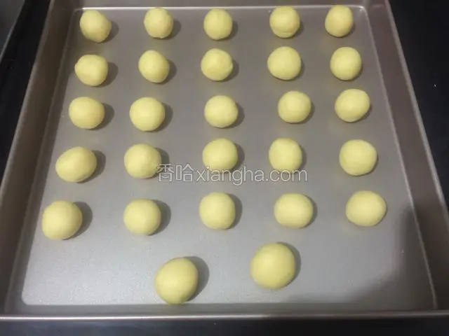 取出冷藏好的面团，分成同样大小的小面团，搓圆排入烤盘里。