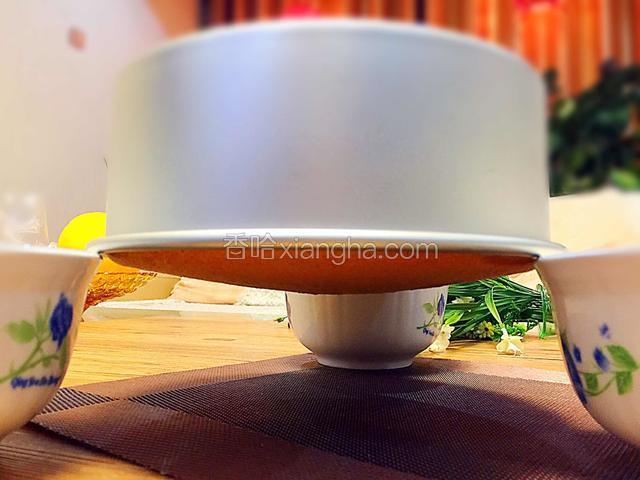 倒扣在烤网上或三个碗上架空起自然凉透，凉透的蛋糕边缘按压一圈，手托模具底往上一托烤好的戚风蛋糕就完整脱模了。