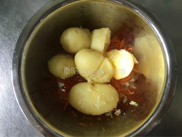 把红萝卜丝放到大碗里，然后把蒸熟的土豆剥皮放进去。