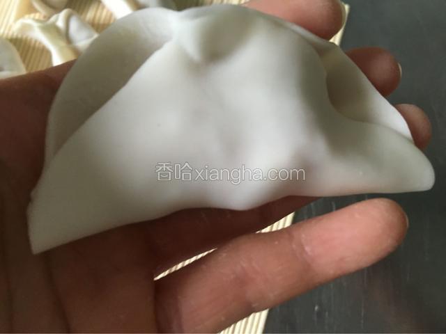 饺子皮对折，在中间处捏实。