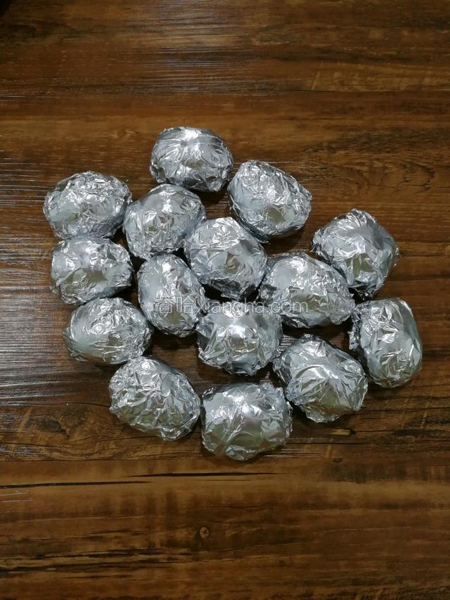 把装好材料的咸鸭蛋，用锡箔纸一个一个的包起来。