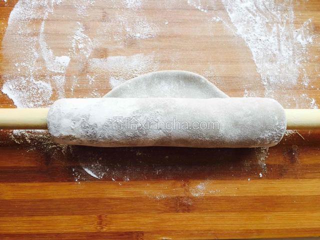 用擀面杖卷起面片的一个边，把面片卷在擀面杖上用手开始擀，擀好一个边打开撒上面粉，继续卷另一个边擀。直到面团变成大的圆的薄的面片。