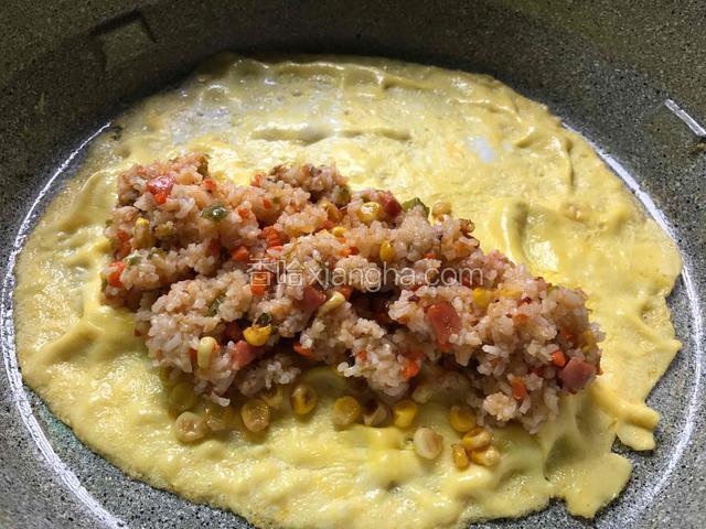 把炒好的米饭铺入鸡蛋的一边