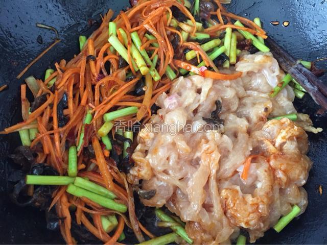 油温热后，下肉丝迅速划炒散开；炒至肉色变白后用铲子将肉丝拨在锅边，然后下入胡萝卜丝和黑木耳丝、蒜苔大火煸炒片刻；