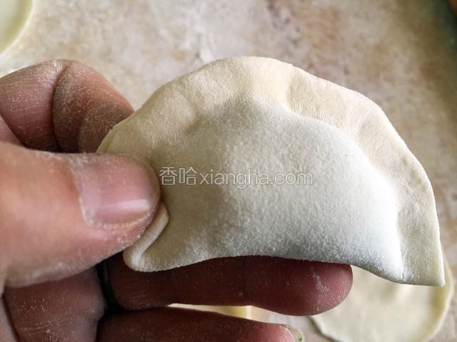 从饺子边缘的一端开始捏花边，用手指肚将饺子边向上翻折捏紧。