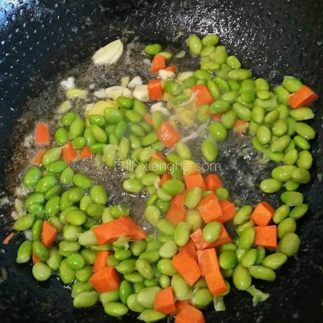 炒虾仁剩下的油放入姜，蒜爆香，倒入毛豆和胡萝卜一起炒，炒偏至变色就可以了