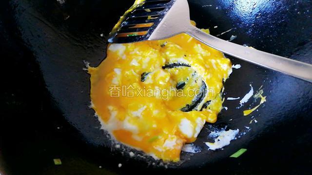 锅中磕入两个鸡蛋，炒熟再盛进盘子里。
