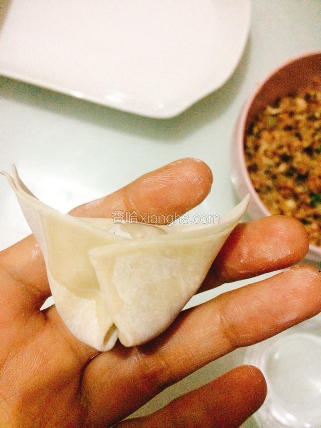 在把下面的两个角粘在一起，这样一个云吞就包好了。