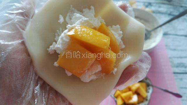 取一个粉团压圆，包入奶油、芒果