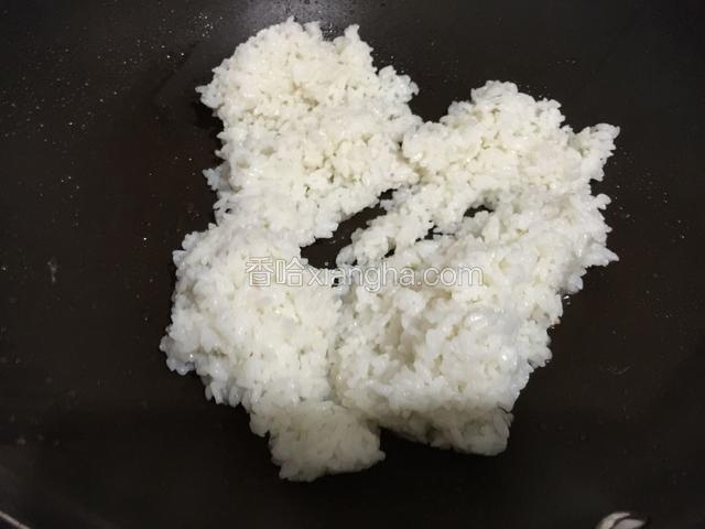 锅中再倒入少许的油，倒入白米饭翻炒两分钟，把白米饭炒散开。