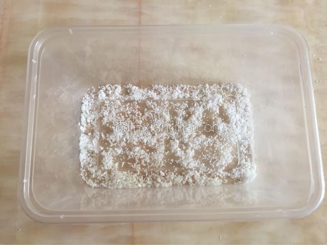 取一个干净无水的保鲜盒，均匀撒上适量的椰蓉。