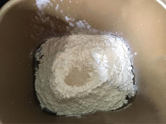把面包机内胆放到电子称上，然后把所有的材料一步一步放入称好，盐和糖对角放，面粉和酵母放上面，如图。再把内胆放回面包机里，开启和面功能，共和面50分钟。