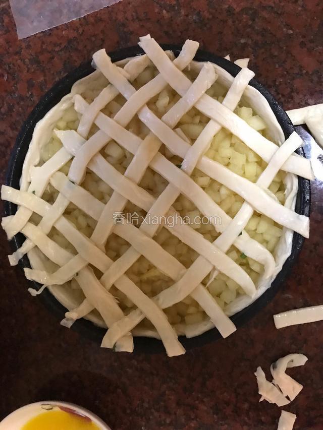 如图编织，并切去多余部分。手抓饼很粘，建议隔着薄膜切，切完已经是很粘了，必须再放回冰箱冷冻柜急冻上几分钟，再拿出来，然后才撕去薄膜，就很轻松了，趁着还没有变粘，赶快编织表面派皮吧。