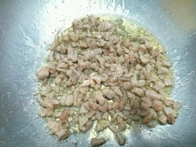 锅内放入适量食用油，烧热后放入猪肉丁，翻炒至肉丁变色断生。