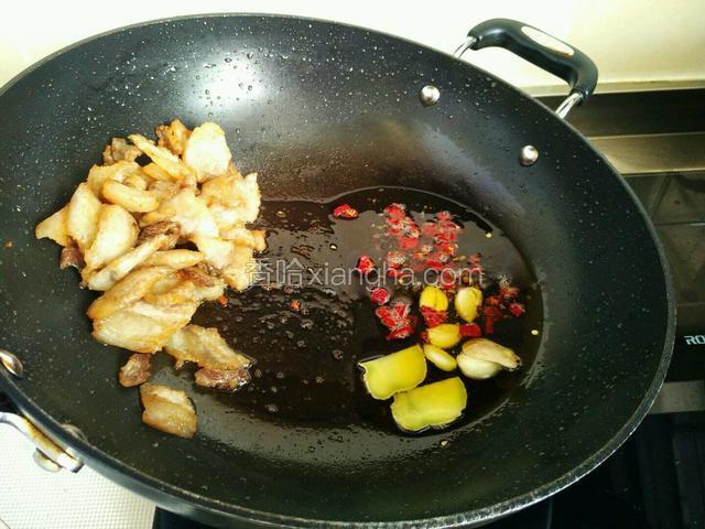 将五花肉推到锅的一边。(如果是油煸花菜的话，现在就可以下锅了)，将锅倾斜，油淌到锅的另一边，放入生姜蒜头和干红辣椒煸香。小火!干红辣椒一定要小火，要不然很容易焦掉。