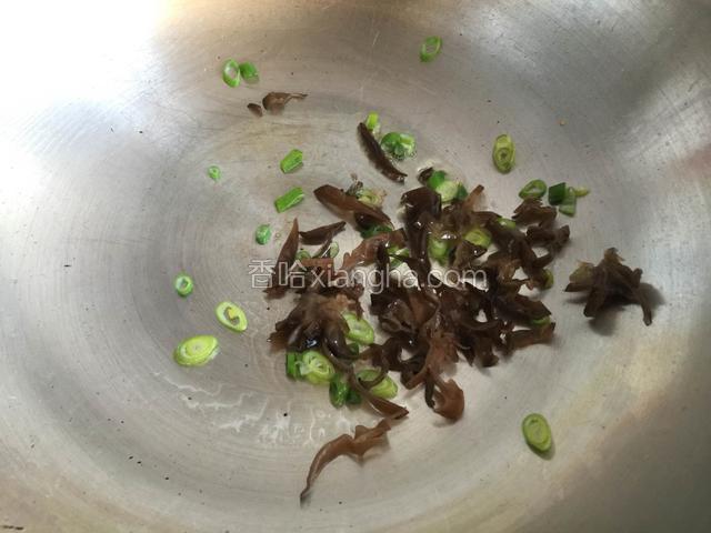 锅内放油烧热，放入葱末和木耳丝略炒片刻。