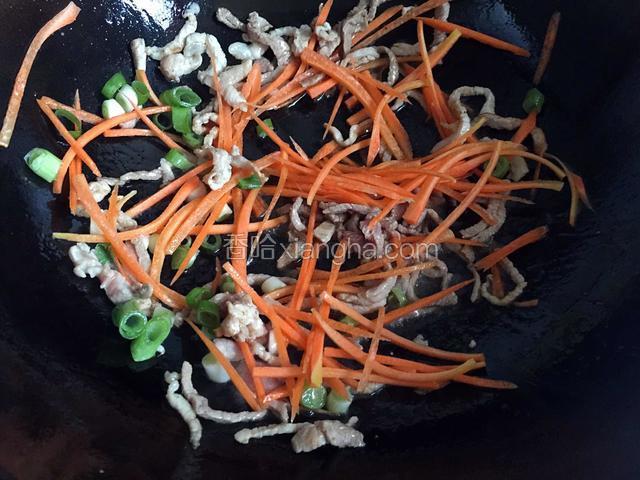 待肉丝变色，放入葱末和胡萝卜丝翻炒片刻。