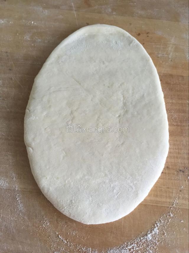 醒好的面团用擀面杖擀成椭圆形