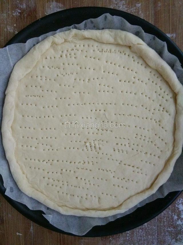取一份面团擀成饼，整理好形状放入披萨盘里，盘底垫油纸，饼中间用叉子扎小孔排气。放入烤箱略烤五分钟，烤箱温度150度。