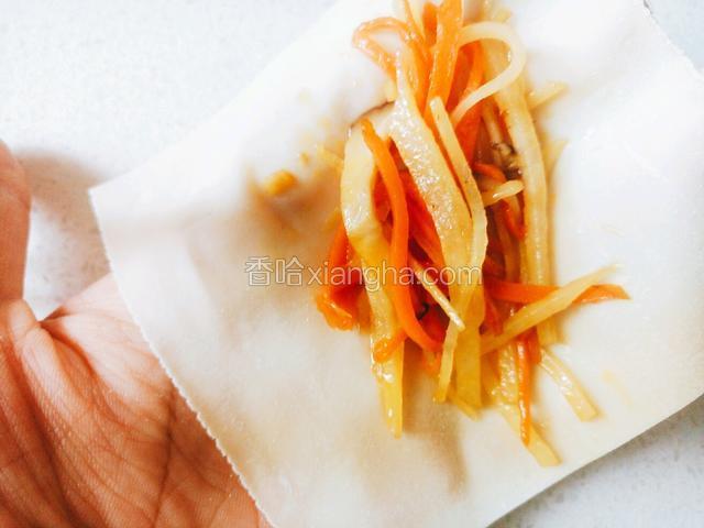 取一个馄饨皮，顺着对角线放上炒好的菜。