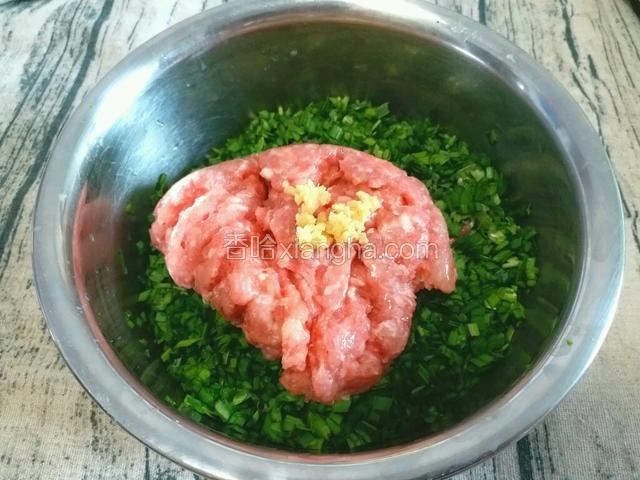 将猪肉馅和姜末放入盛韭菜末的盆中。