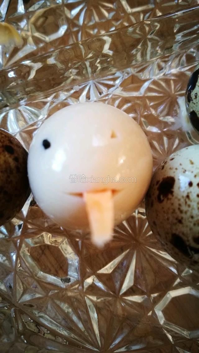 看图，将鹌鹑蛋的小头中间用小刀横切，然后将切好的长三角胡萝卜插进鹌鹑蛋的嘴里，在嘴的上方用小刀扎两个小洞，把黑芝麻放里。