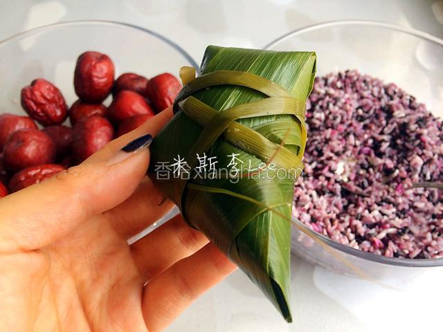 一手固定粽子，一手用马莲捆紧，至少要有一次交叉捆绑，才不容易松脱，最后留出一定长度系活扣；