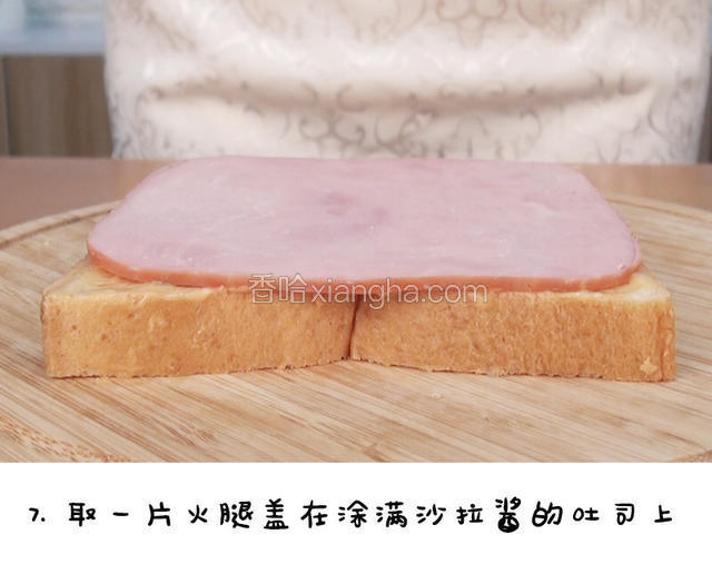 取一片火腿，盖在涂满沙拉酱的吐司上