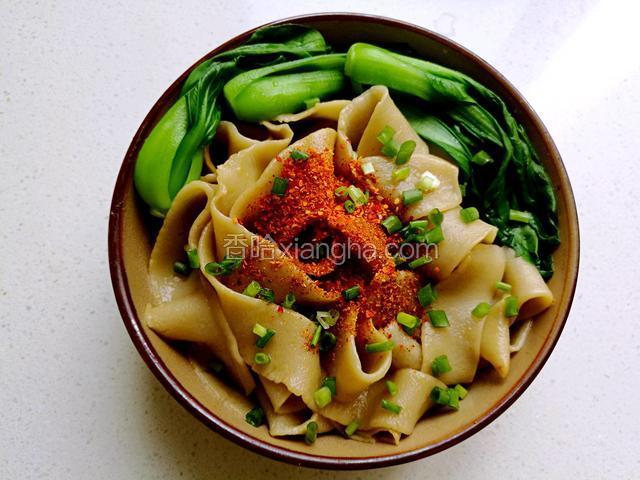 然后在面条上面摆上烫好的小油菜，撒上辣椒粉和花椒粉，再撒上小香葱。