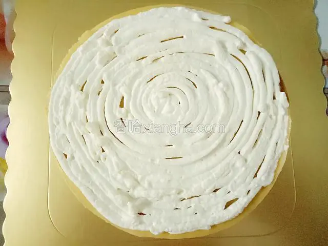 取一张凉透的饼皮，光滑的一面朝上，挤上一层淡奶油