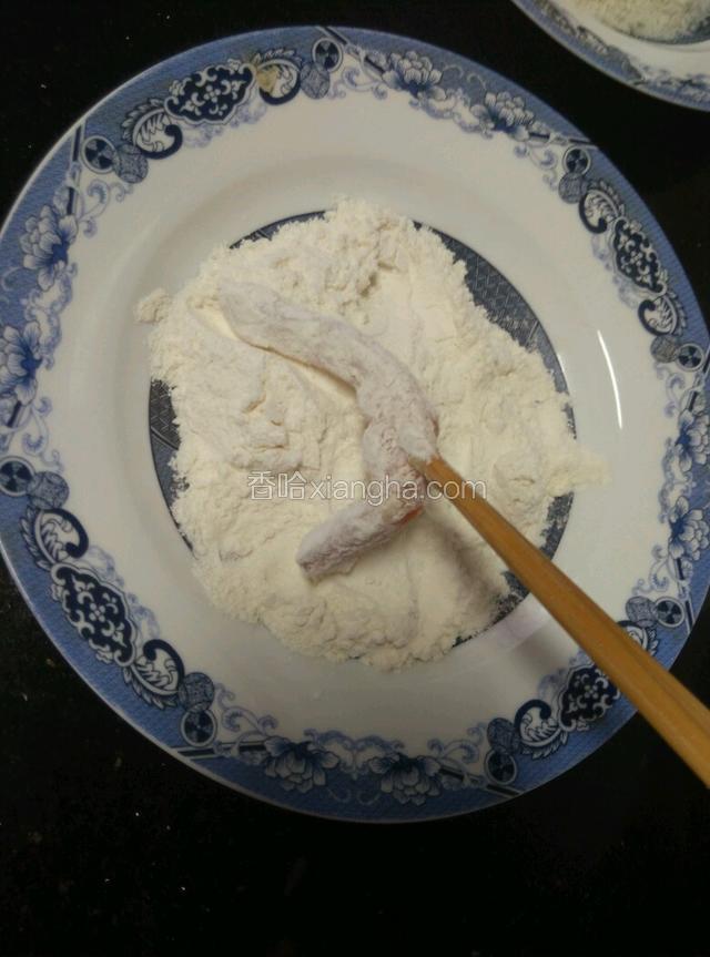 把腌好的鸡柳沾上一层面粉，把多余的面粉拍掉。