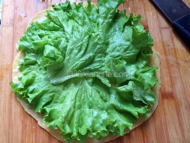 取一张饼，放上生菜叶。